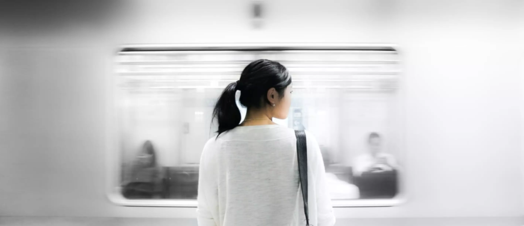 A woman watches a train pass in Tokyo Japan.