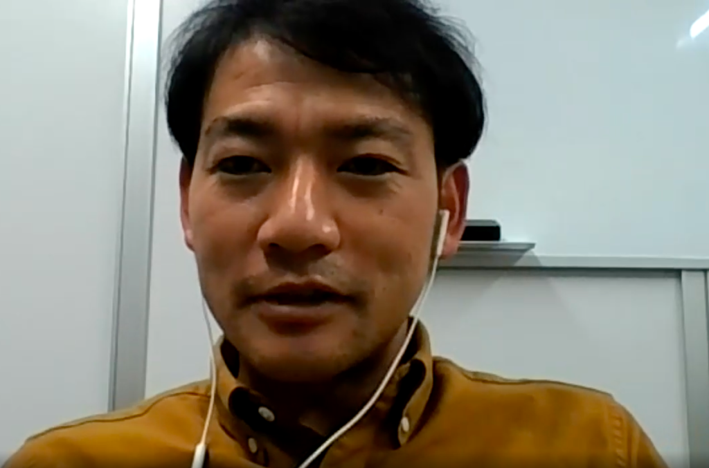 A man wearing a yellow shirt who is doing remote work in Japan.